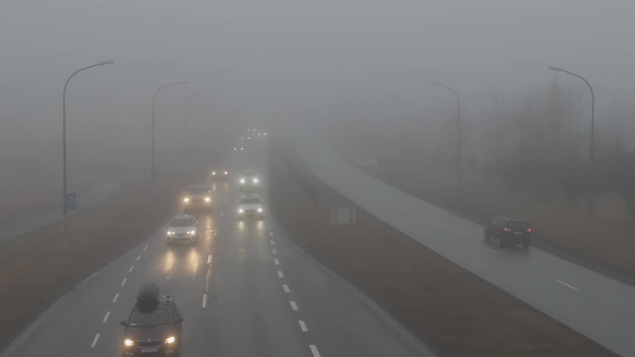 冰岛雷克雅未克，车辆在浓雾中行驶在柏油路上视频下载