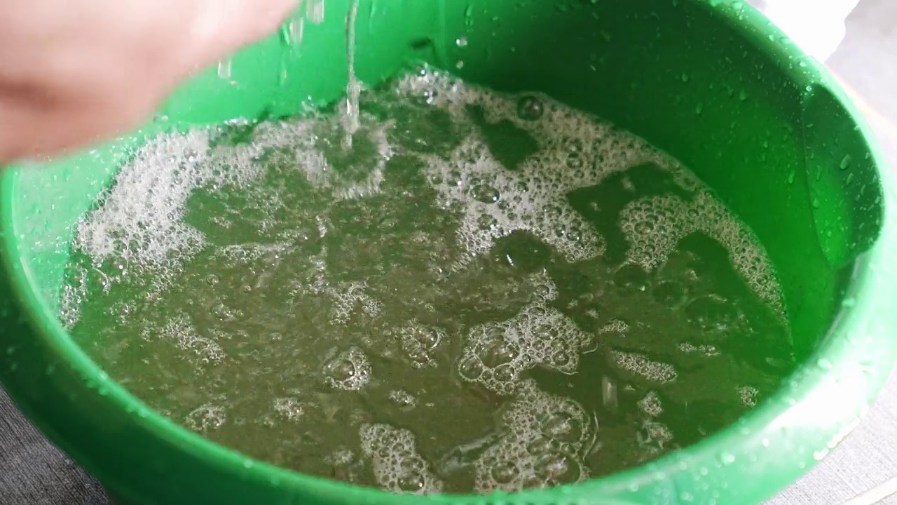 由于浴室漏水，一名男子用抹布在桶里收集水。视频素材