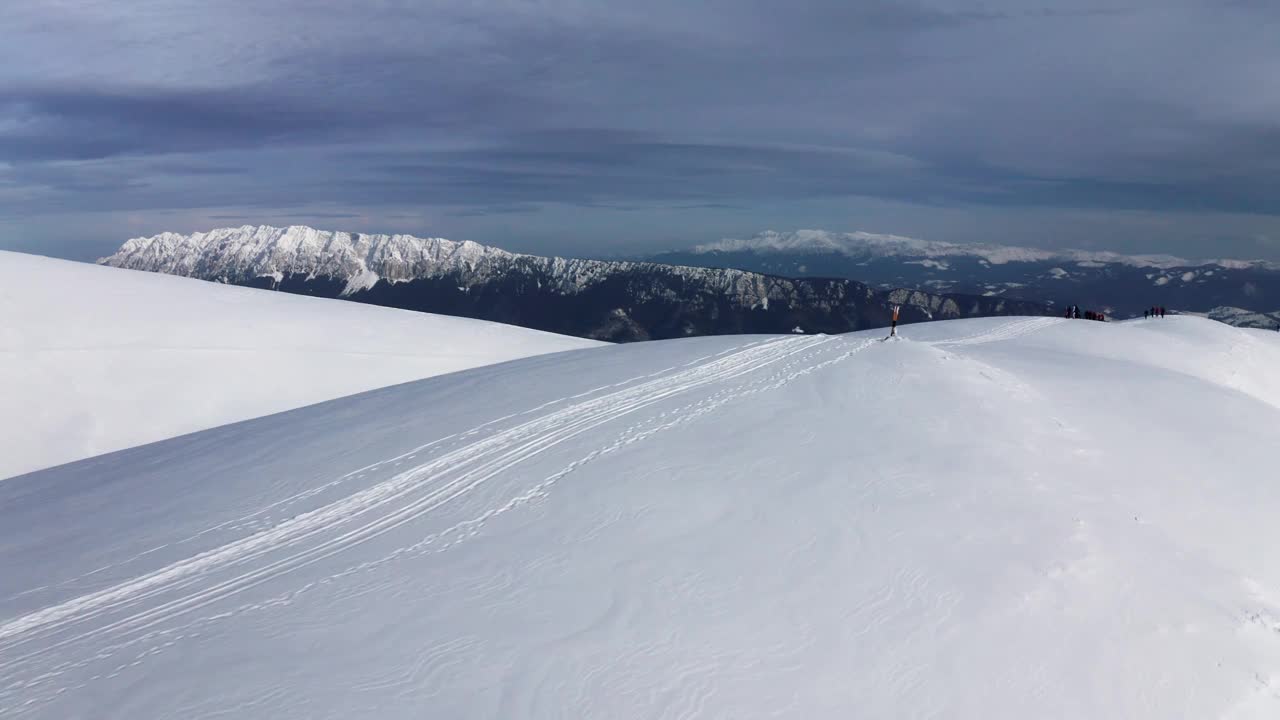 白雪皑皑的山脊与远处的Piatra Craiului，伊泽-帕普萨，阿尔日，罗马尼亚，晴朗的天空下视频素材