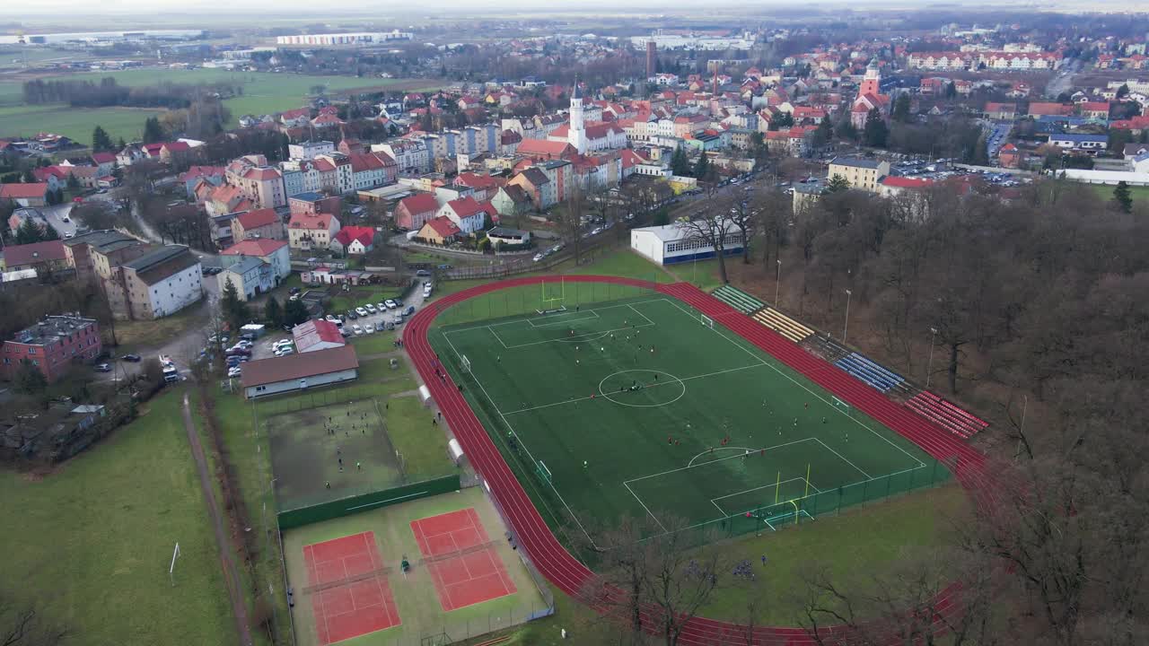 小镇体育场鸟瞰图，球员在足球场上踢足球视频下载