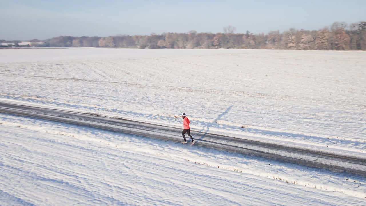 男跑步者在冬天下雪的路上慢跑视频下载