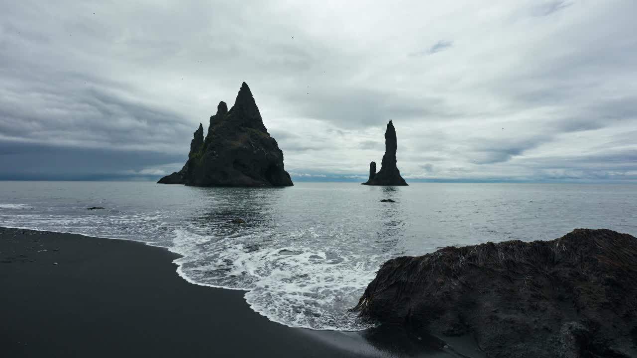 Moody Reynisdragar在冰岛维克大西洋的Reynisfjara黑沙滩上与天然岩石形成视频下载