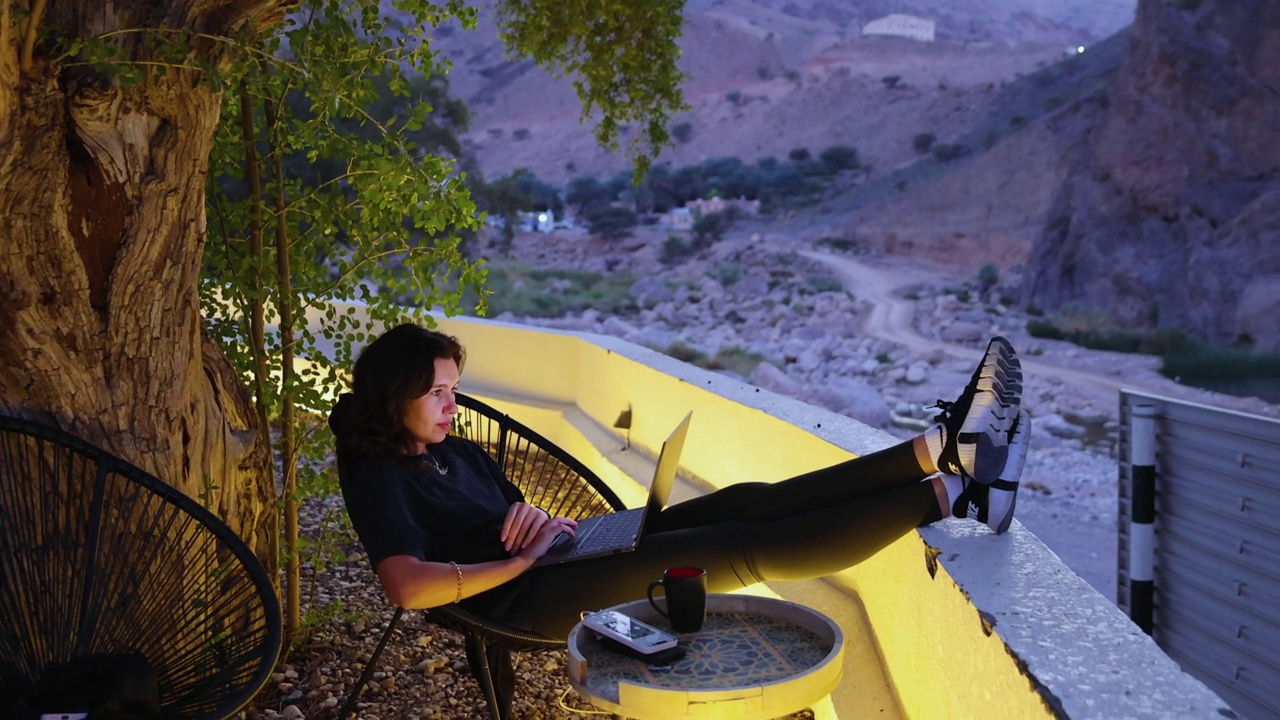 在山区旅行期间，女性自由职业者在户外用笔记本电脑工作视频下载