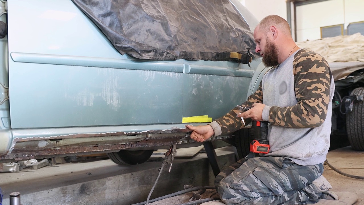 修理工清除汽车门板表面的铁锈。视频下载