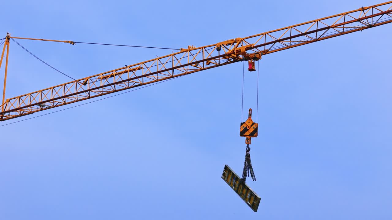 蓝天下工地建筑平台上起重机为工人降下建筑材料的无人机拍摄视频素材