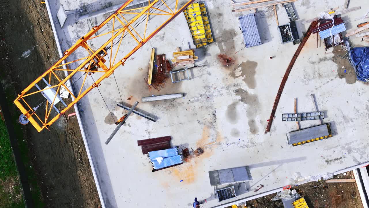 空中无人机在现场拍摄的大型起重机在未完工的建筑物上搬运建筑材料视频下载