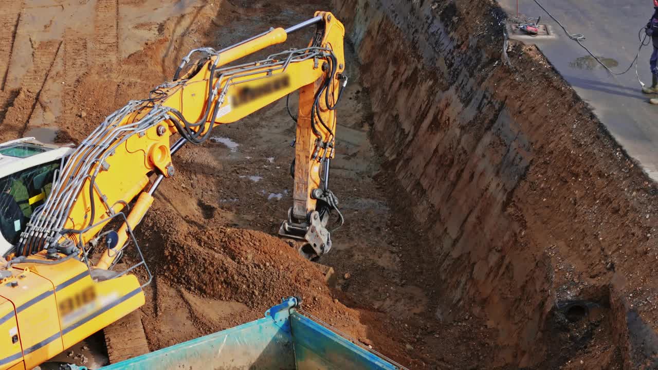 无人机拍摄的挖掘机装载卡车与沙子在建筑工地视频下载