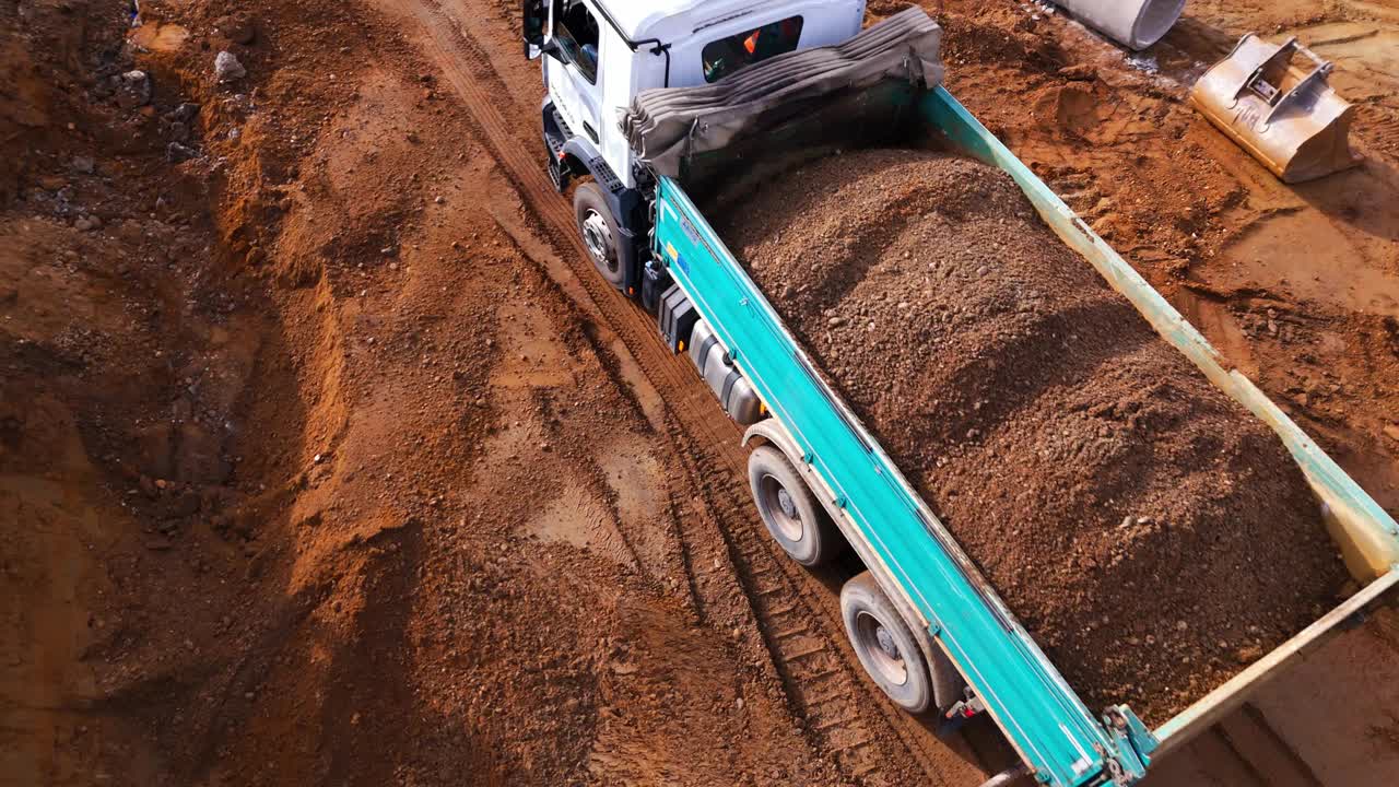 无人机拍摄的自卸卡车装载沙子在工地行驶视频下载