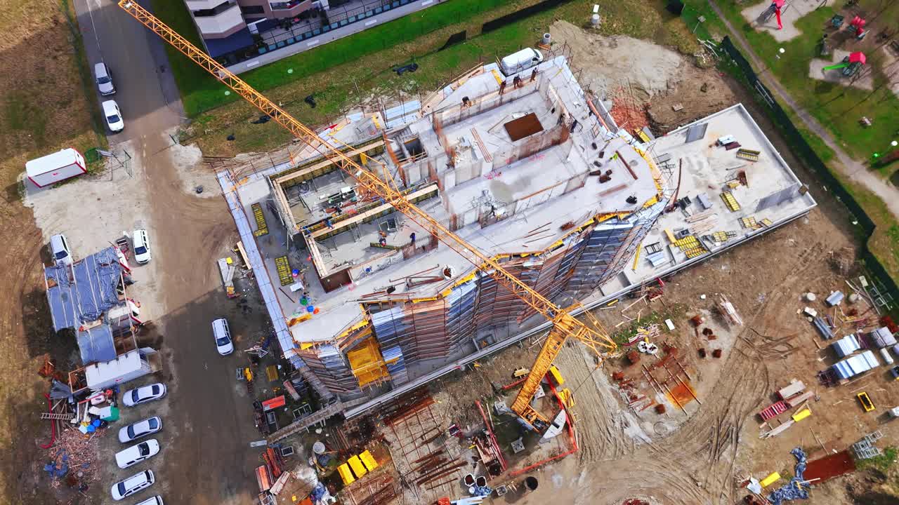 无人机拍摄的建筑工人和大黄起重机在城市未完工的建筑物视频素材