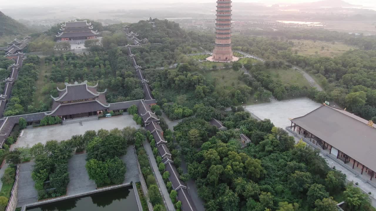 夕阳下，在越南宁平的一个佛教寺庙和长满绿树的宝塔上空，无人机的鸟瞰图视频素材