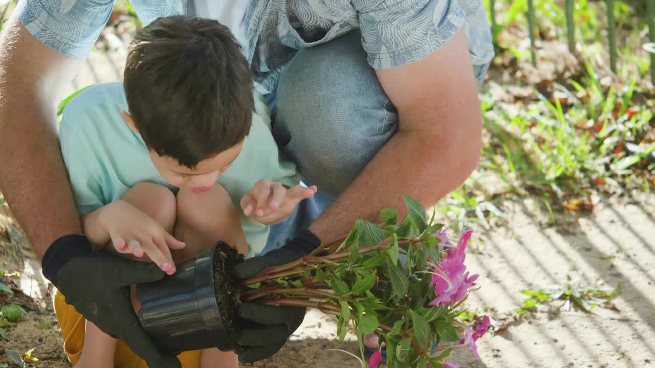 父亲带着患有唐氏综合症的儿子在花园里种花视频下载
