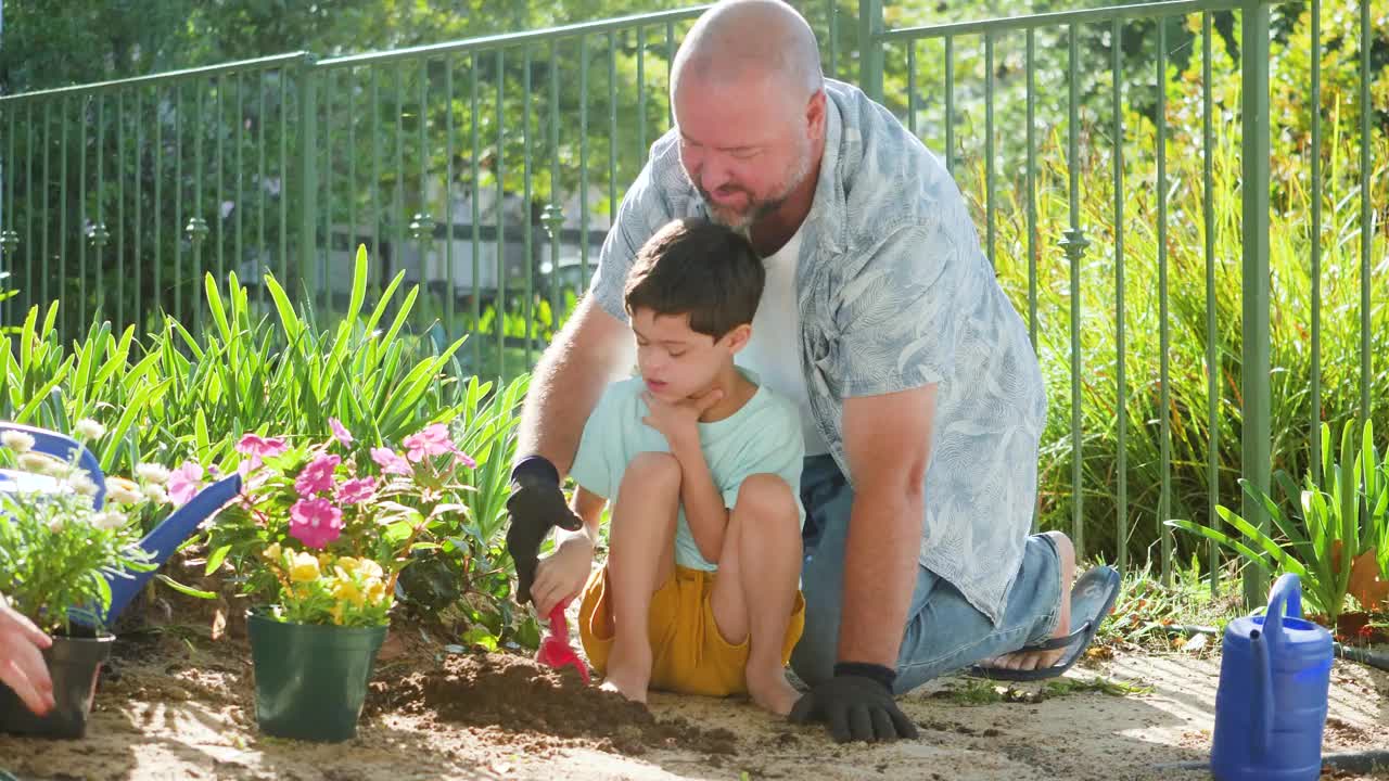 父亲带着患有唐氏综合症的儿子在花园里种花视频下载