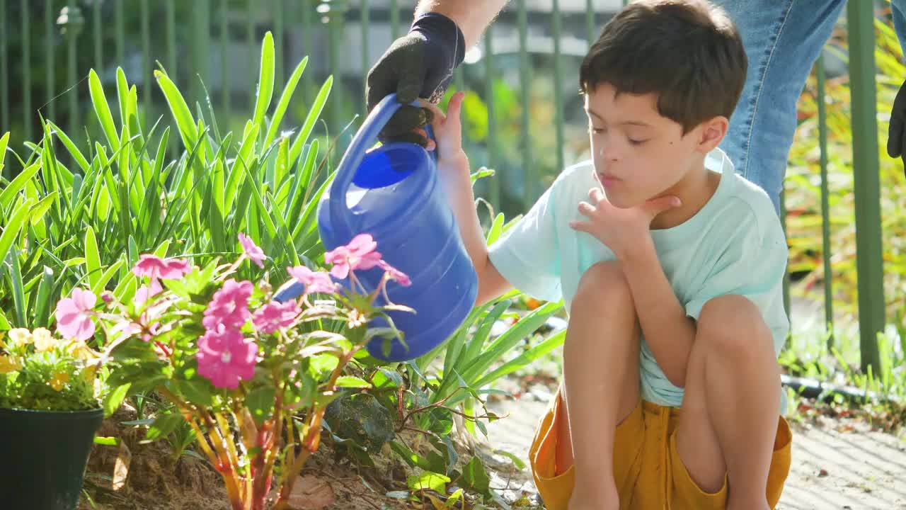 父亲带着患有唐氏综合症的儿子在花园里浇花视频下载