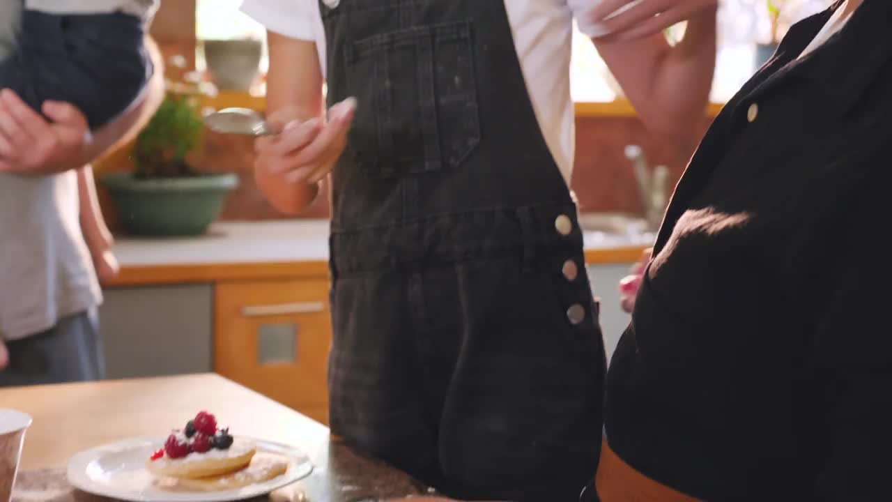 微笑的女孩拥抱着妈妈，在厨房里享用煎饼视频下载