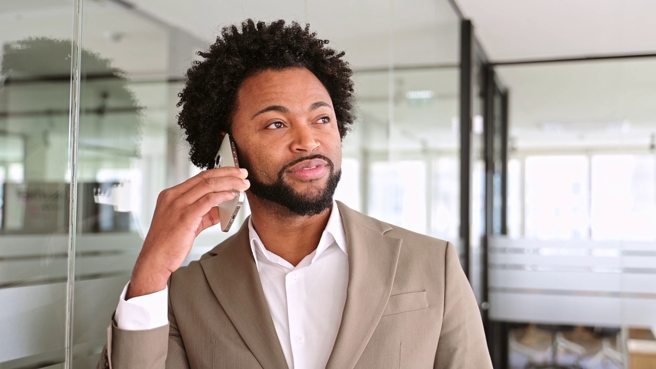 一位深思熟虑的非裔美国商人在一间明亮、现代化的办公室里接听电话视频下载