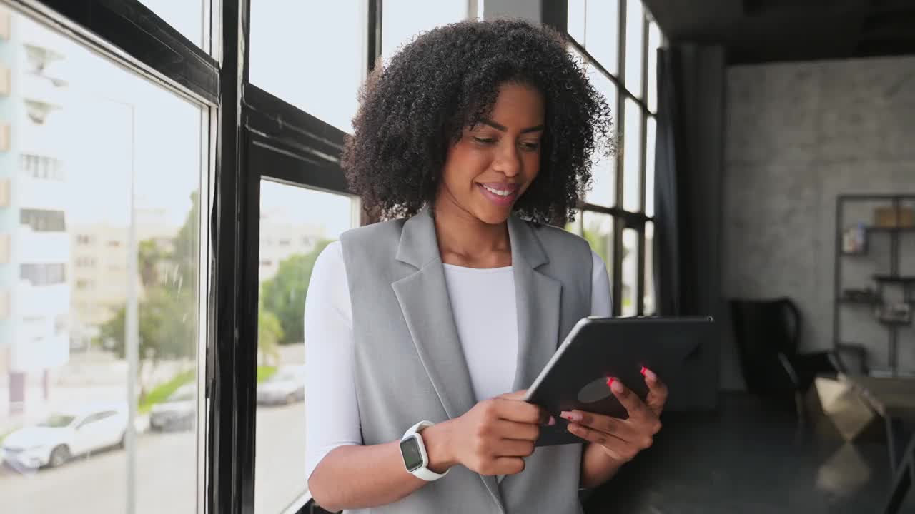 一位身穿职业装、容光焕发的非裔美国女性对着她的平板电脑微笑视频下载
