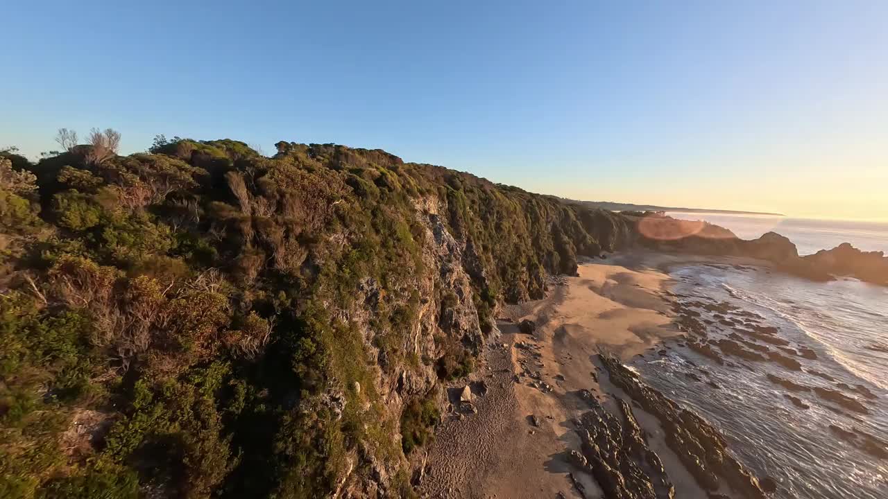 从空中俯瞰悬崖边的树木和两个人在看日出。视频下载