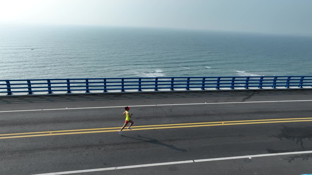 航拍画面，女子在日出的海边大桥上奔跑，慢动作视频下载