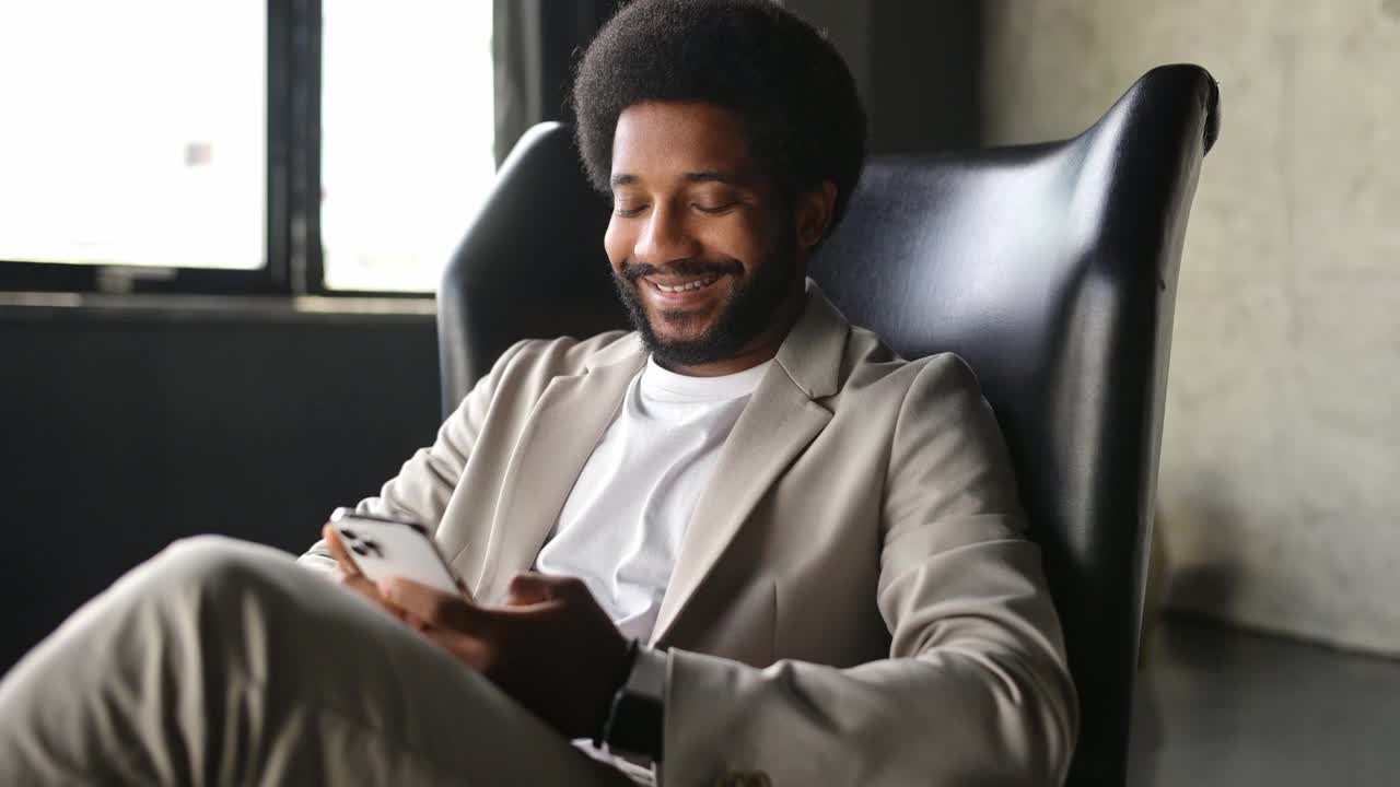 一位神情轻松、面带微笑的巴西商人正在享受他的智能手机时光视频下载