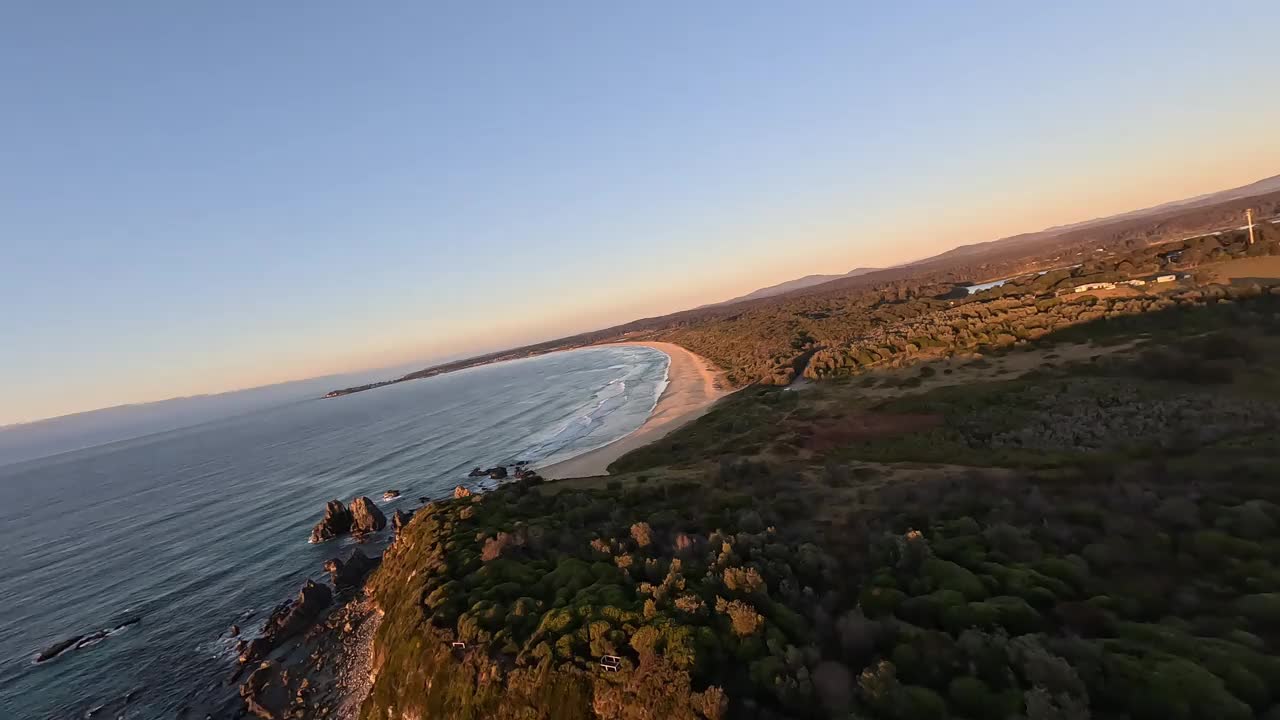 日出时站在悬崖岬角上的两个人的鸟瞰图。视频下载
