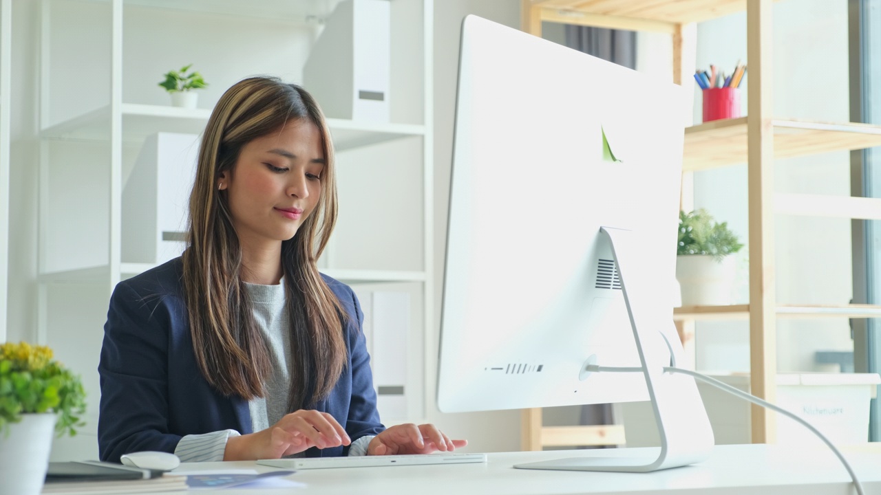 年轻的亚洲女性在办公室使用台式电脑视频下载