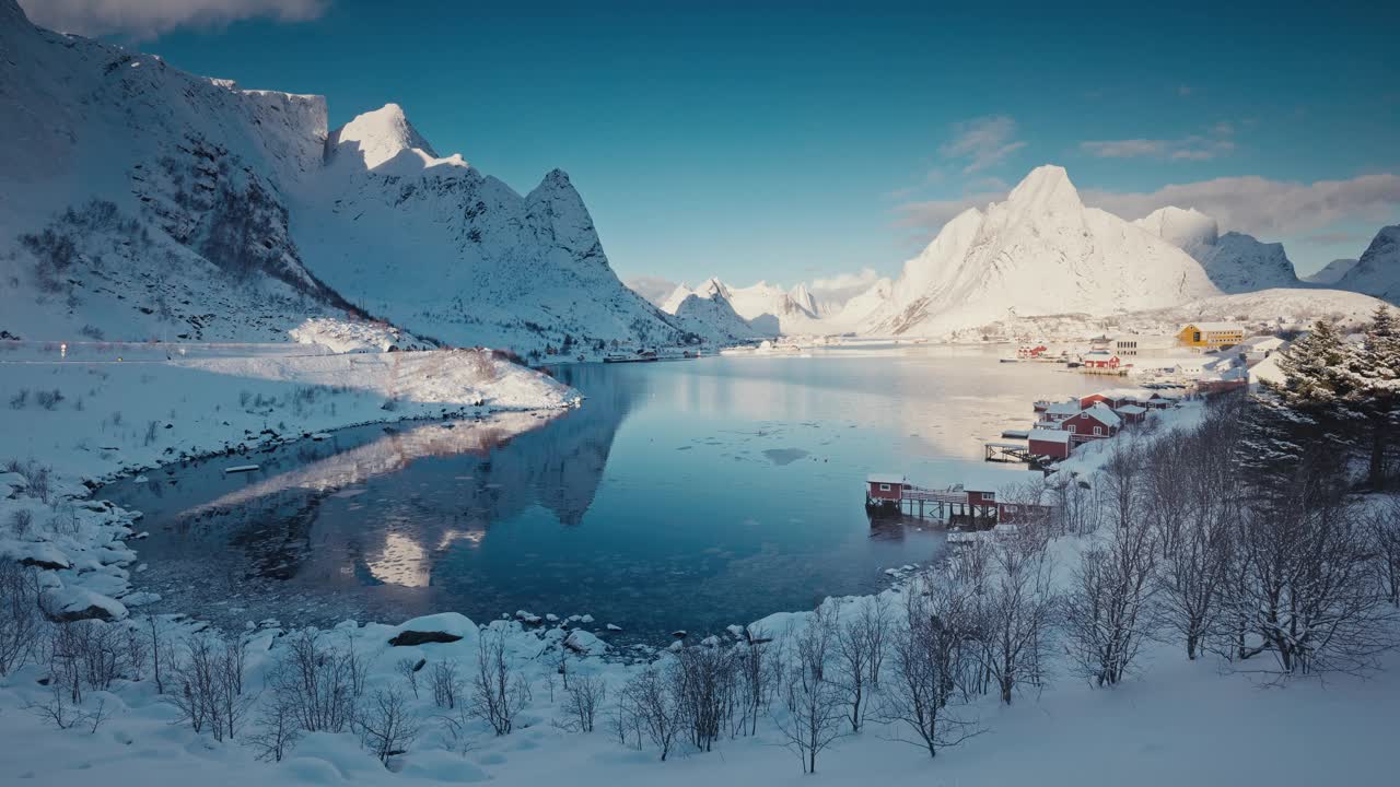 全景冬季景观，白雪皑皑的山脉和被雪覆盖的萨克里索伊村，以及挪威罗弗敦群岛的北欧建筑房屋视频下载