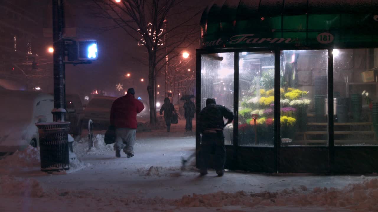 大雪中，一名男子正在铲走人行道上的雪视频下载