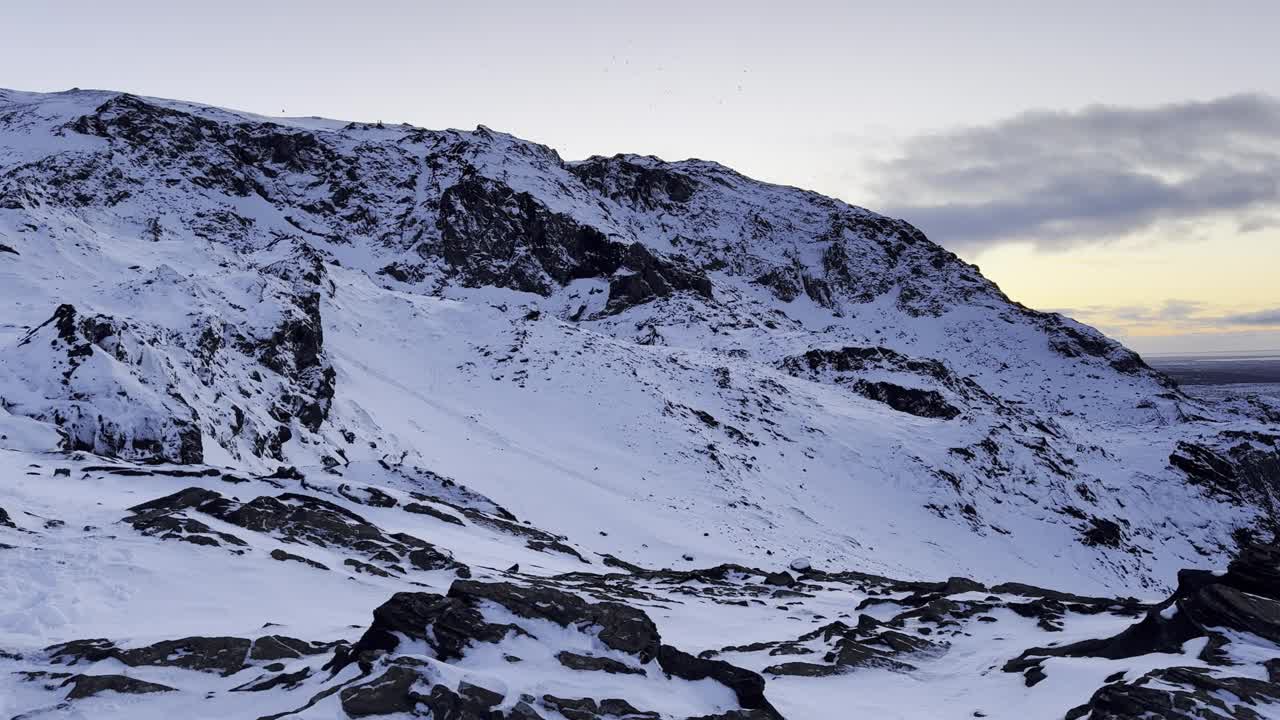 白雪覆盖的山与岩石的前景，多云的天空在背景视频下载