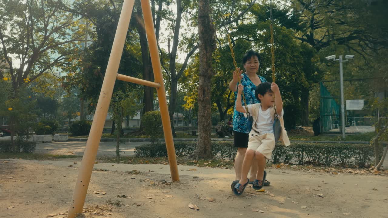 亚洲男孩在操场荡秋千:在阳光明媚的户外捕捉童年的乐趣。视频下载