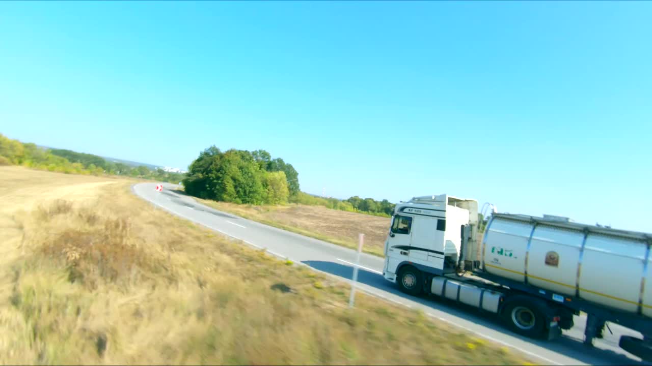 航拍的卡车与货物拖车行驶在道路上和运输货物。飞过在农村高速公路上行驶的送货卡车。工业用车到目的地。物流的概念视频下载