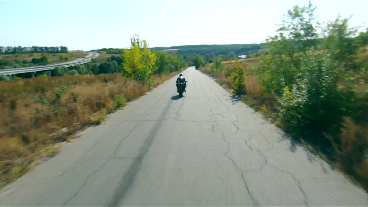 跟随摩托车手骑在现代运动摩托车在农村路线。骑摩托车的人在乡间公路上比赛摩托车。旅途中骑自行车的人。在旅途中自由和冒险的概念。空中拍摄视频下载