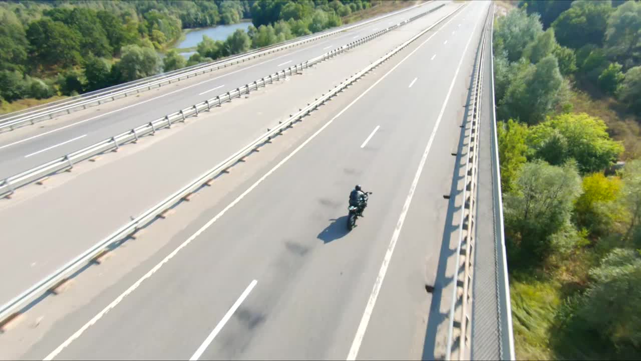 夏日，骑摩托车的人在公路旅行中驾驶摩托车。男子在高速公路上快速骑着现代运动摩托车。摩托车手在乡间小路上飙车。冒险的概念。空中拍摄视频下载