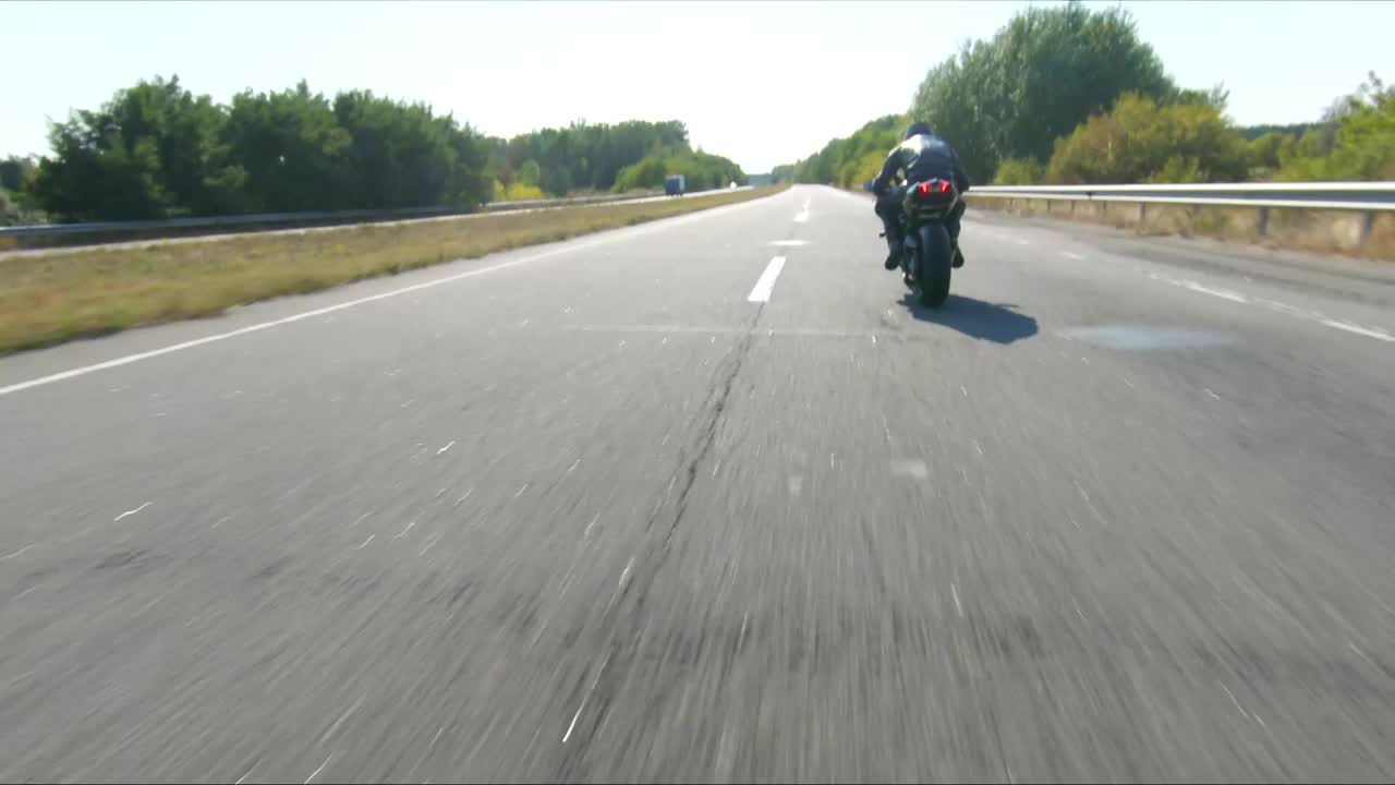 夏日，骑摩托车的人在公路旅行中驾驶摩托车。男子在高速公路上快速骑着现代运动摩托车。摩托车手在乡间公路上驾驶摩托车。冒险的概念。空中射击。视频下载