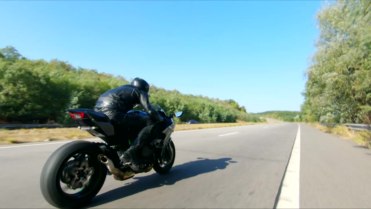 空中拍摄的男子骑着现代运动摩托车在高速公路上在夏天的一天。摩托车手在乡间公路上驾驶摩托车。有人在旅途中骑自行车。自由和冒险的概念视频下载