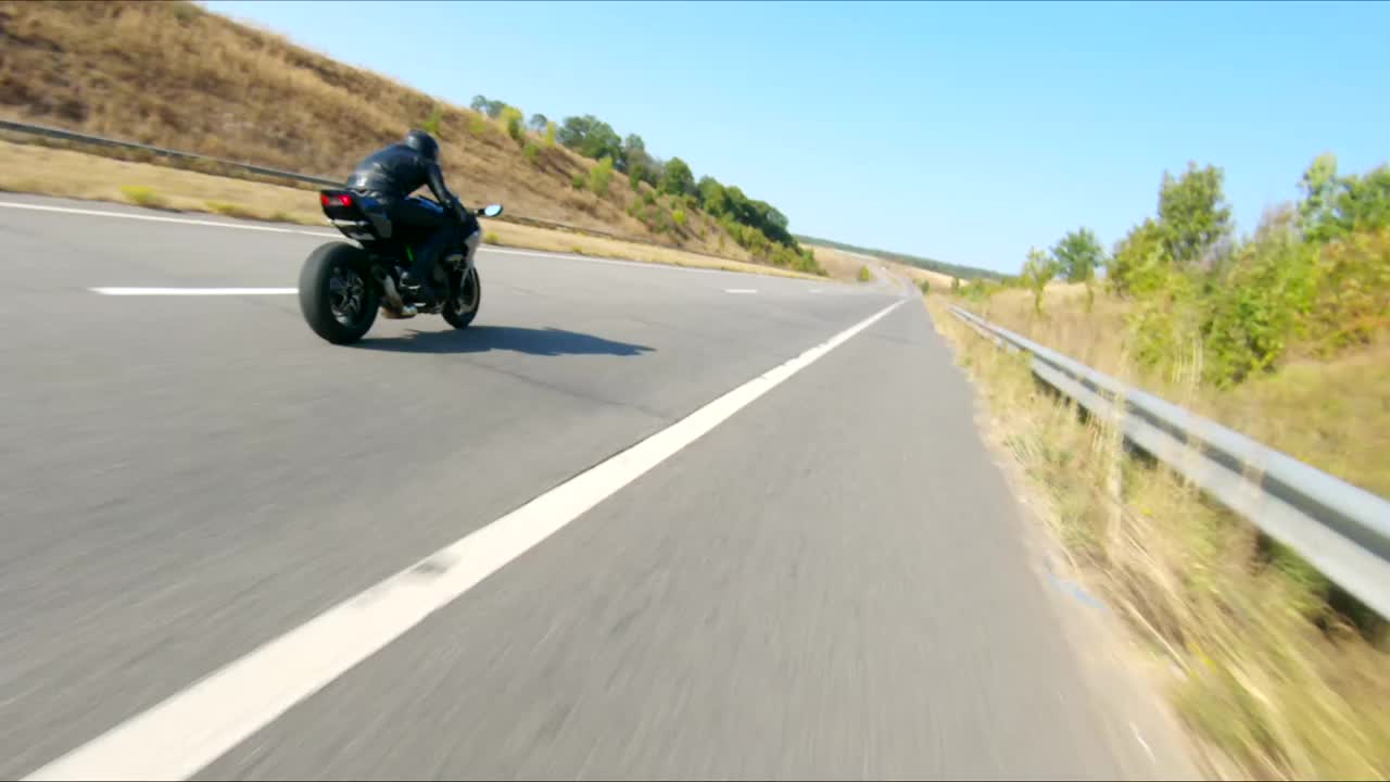空中拍摄的男子骑着现代运动摩托车在高速公路上在夏天的一天。摩托车手在乡间公路上驾驶摩托车。有人在旅途中骑自行车。自由和冒险的概念视频下载