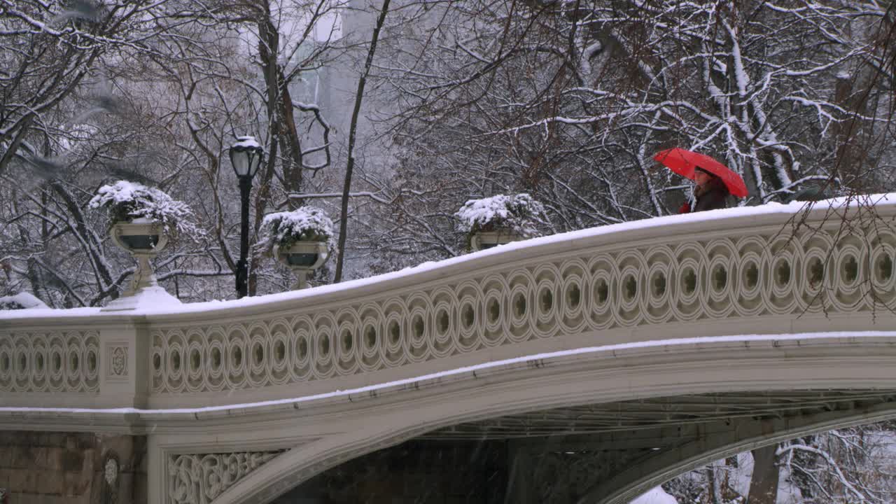 雪地里的桥上，打着红伞的女人视频下载