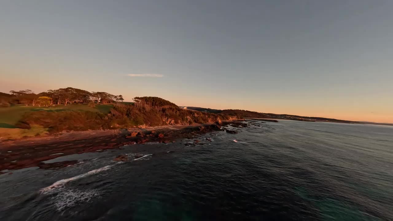日出时悬崖底部岩石海岸线的鸟瞰图。视频下载