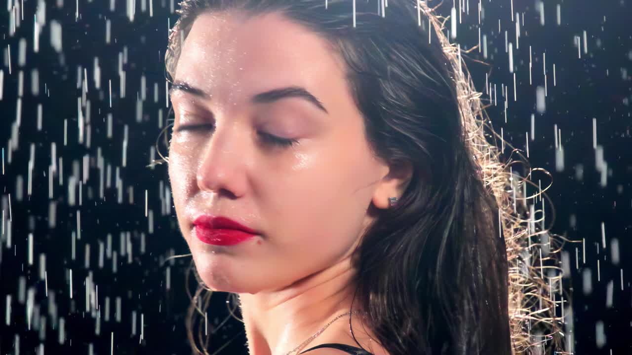 涂着红色口红的女人在倾盆大雨中转过身来视频下载