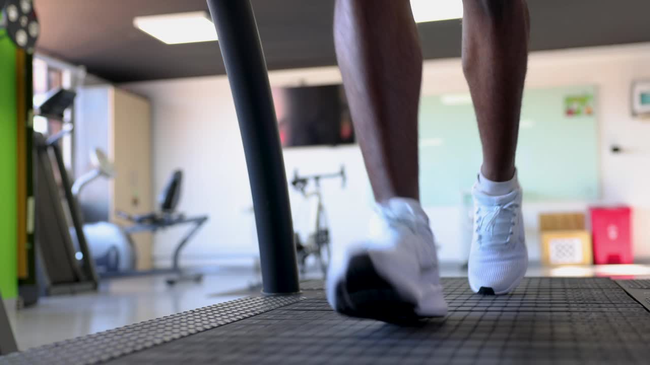 一个人在健身俱乐部的跑步机上跑步的特写视频下载