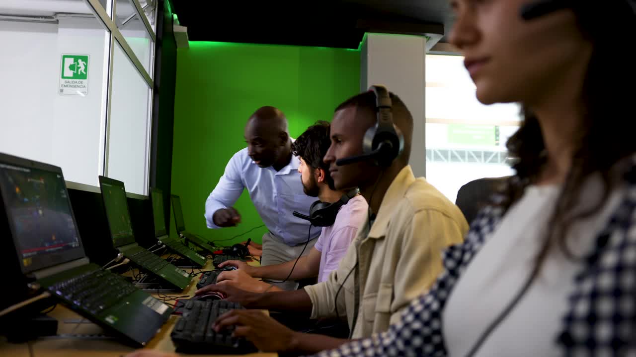 在大学的电子竞技课上，黑人男老师向男病人解释如何进行游戏视频下载
