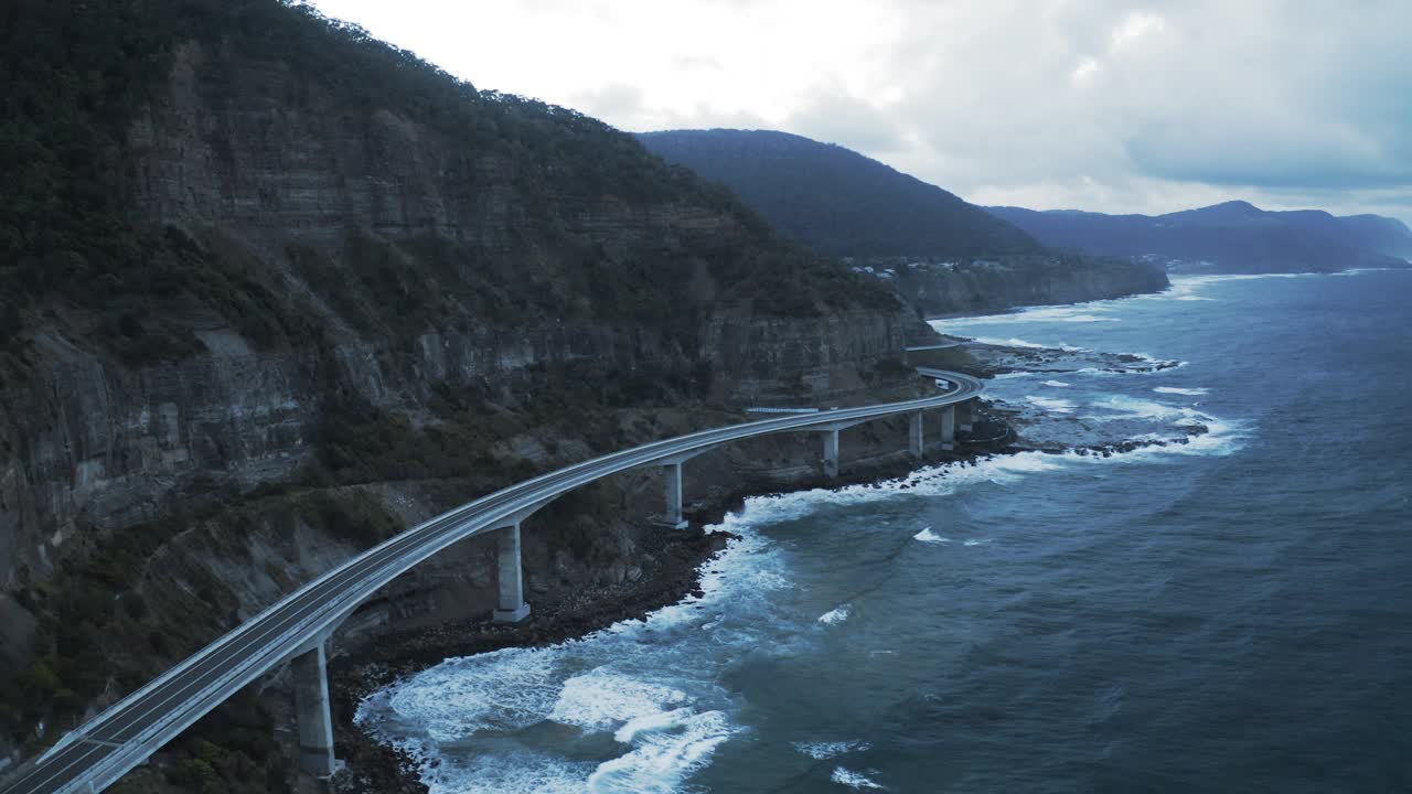 空中拍摄著名的海崖桥岩层，无人机在云层下飞越波浪海-卧龙岗，澳大利亚视频素材