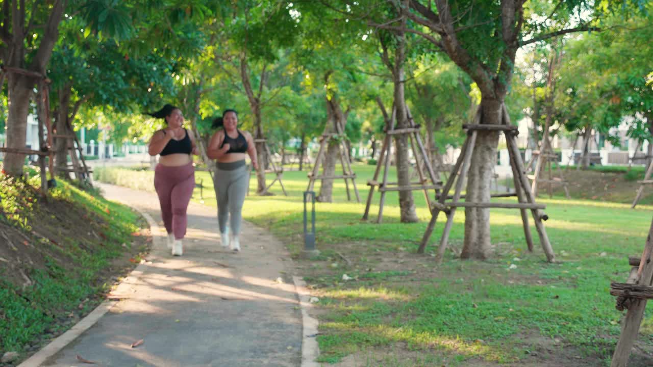 两个肥胖的亚洲女性穿着运动服在公园的小路上慢跑，肥胖的女性和朋友们一起做有氧运动或跑步，锻炼和锻炼，加上身材和健康减肥。视频下载