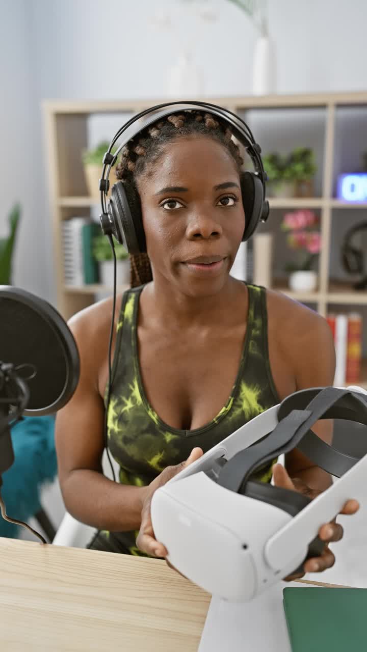 一名梳着辫子戴着耳机的非裔美国女性在演播室里拿着虚拟现实耳机视频下载