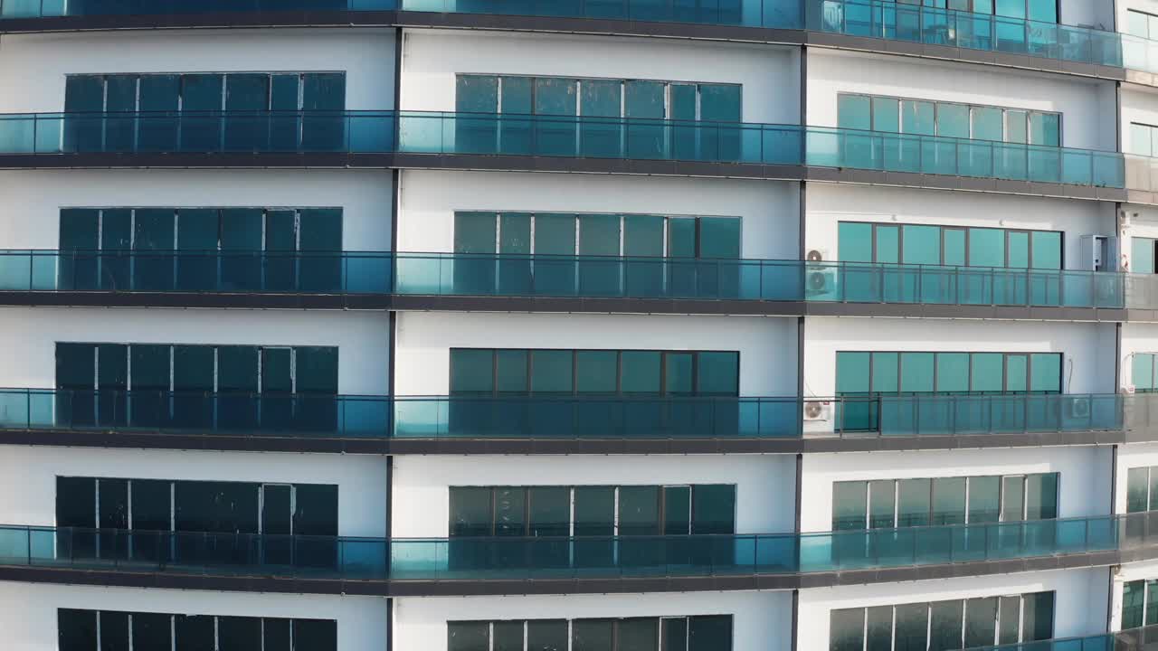 现代高层公寓大楼的无人机鸟瞰图，有清晰的蓝色阳台和城市环境视频下载