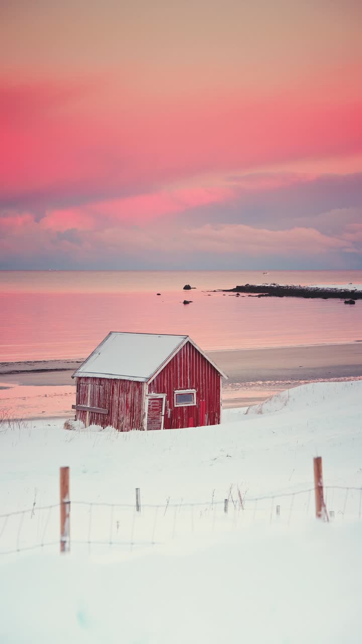 挪威罗弗敦群岛，海滩、海岸和山脊上斯堪的纳维亚红房子的冬季彩色日落视频下载