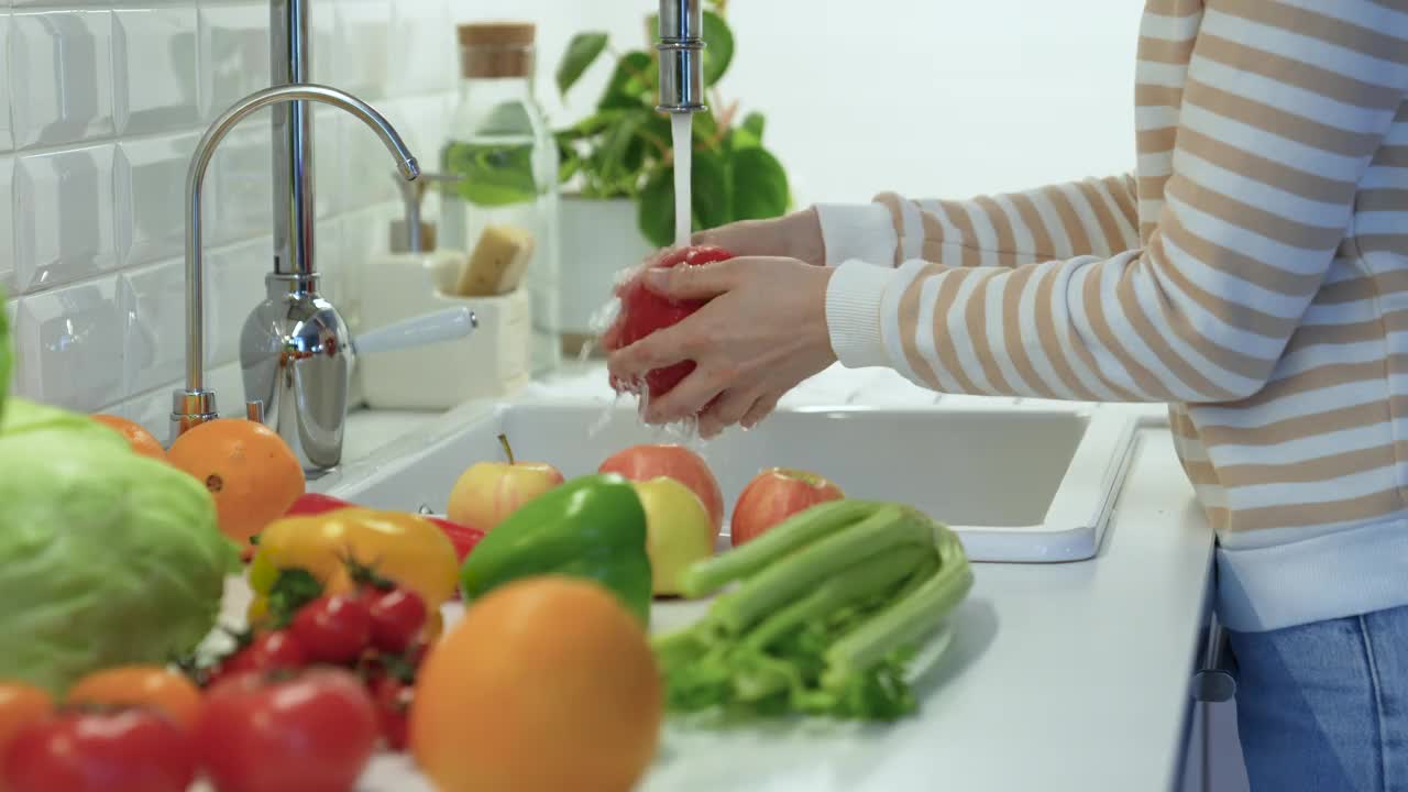 在厨房水槽里用手洗新鲜的蔬菜辣椒。健康的素食生食。视频下载