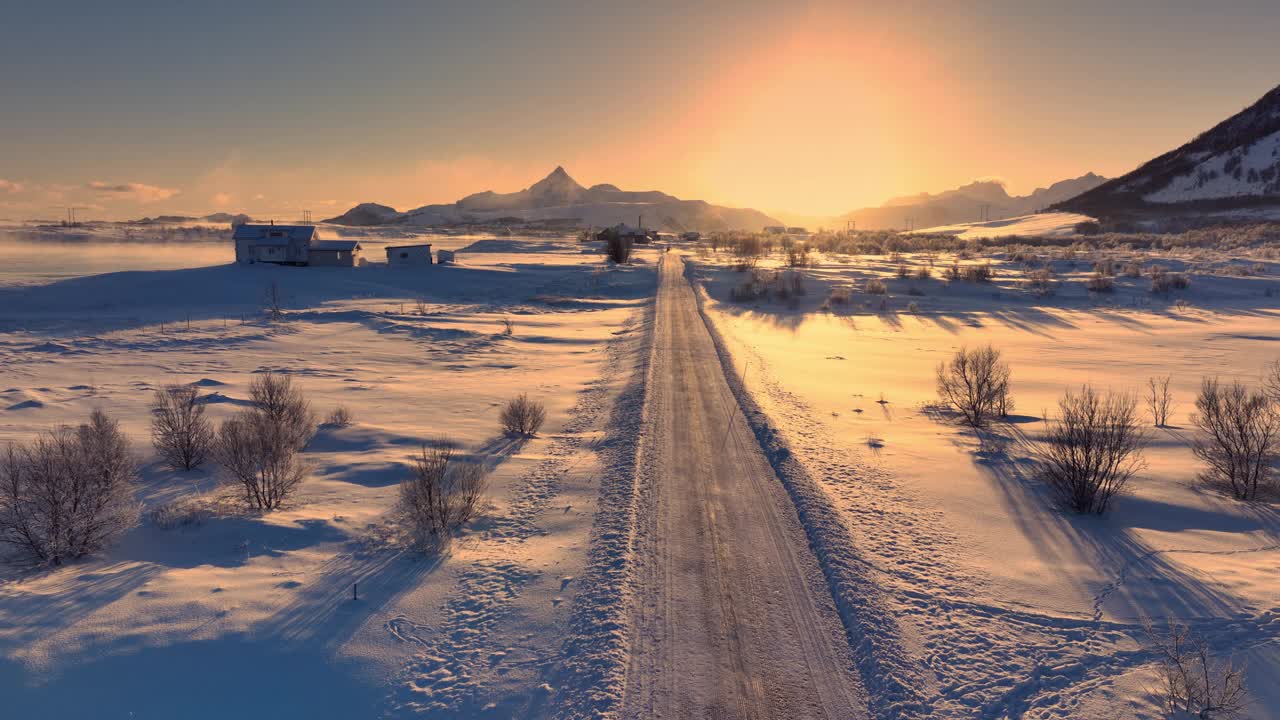 在壮观的日落和日出中，快速驾驶汽车在极地冬季道路上飞溅的雪花，穿越挪威罗弗敦群岛视频下载