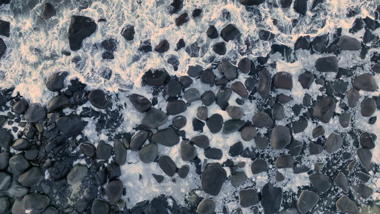 挪威罗弗敦群岛峡湾的岩石海岸，从空中俯瞰花岗岩黑色冰冻岩石上飞溅的海浪视频下载