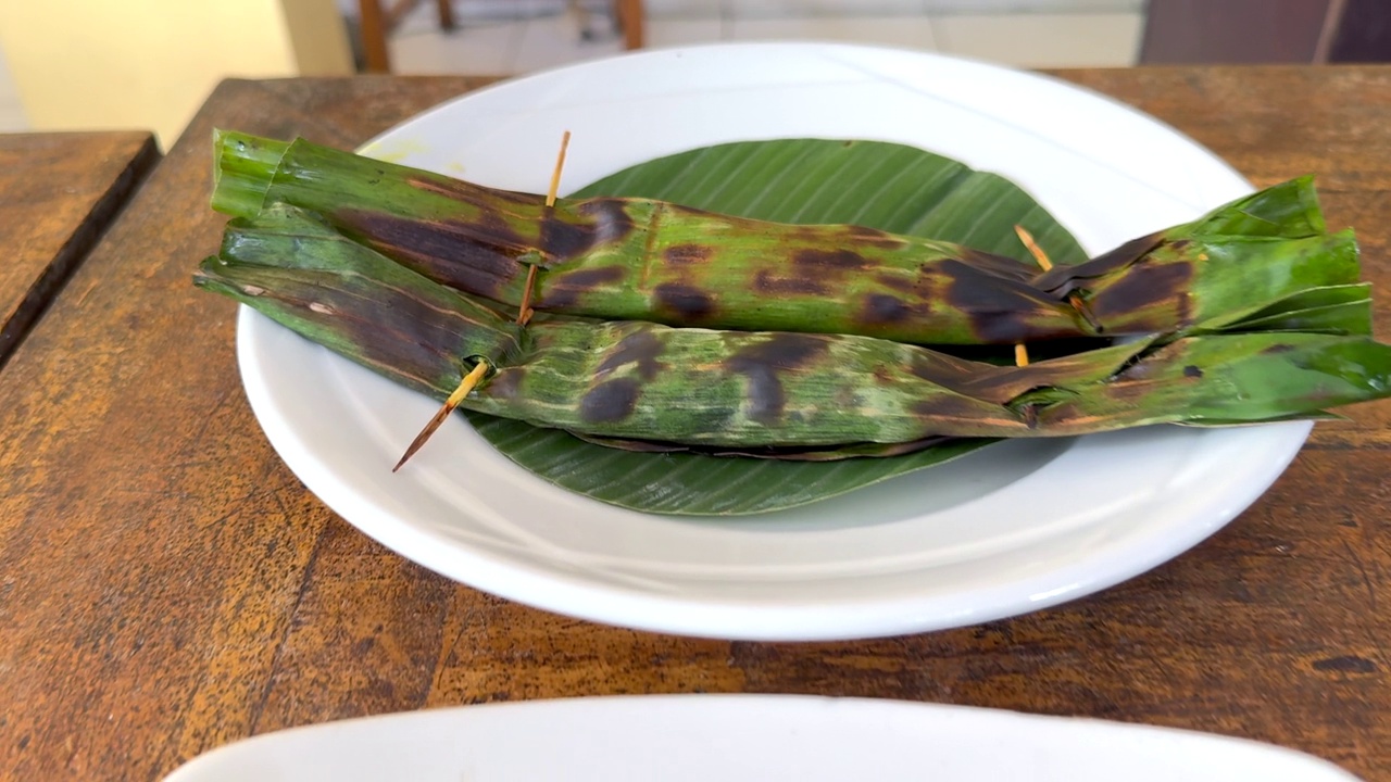 传统的巴厘岛食物美味的鸡肉沙茶条和香蕉叶烤金枪鱼炒面，午餐供应视频下载