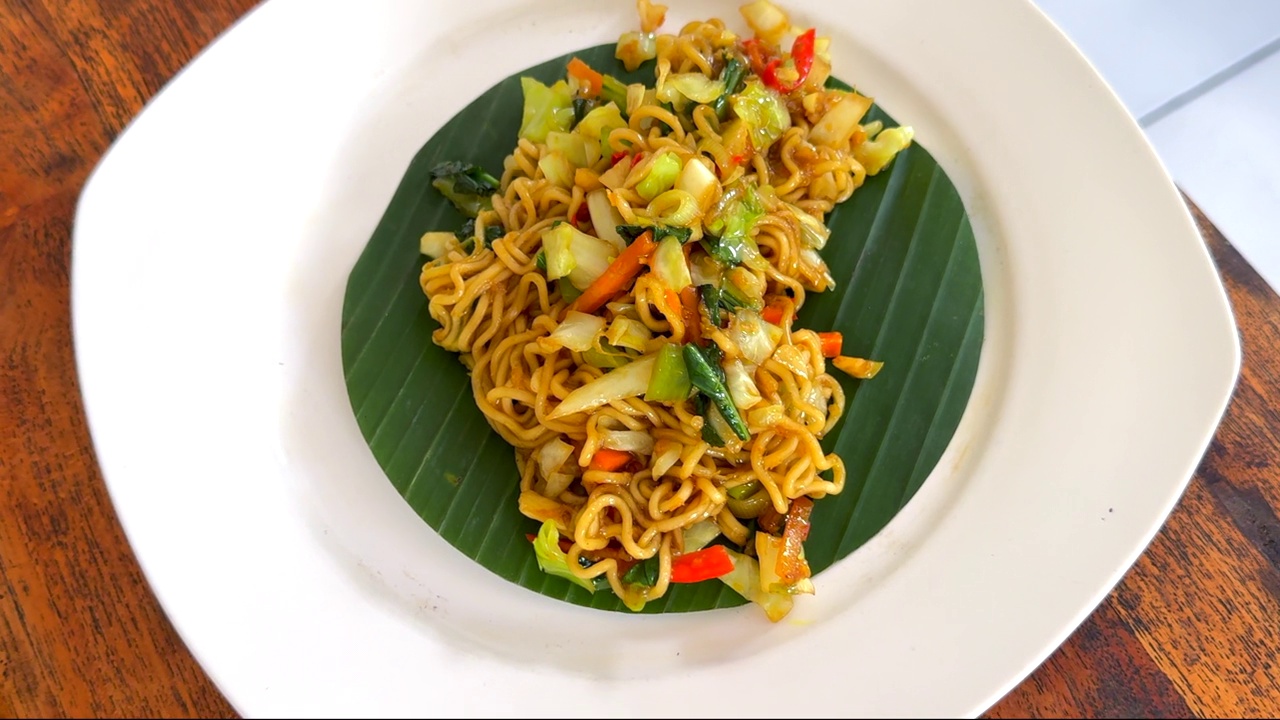 热腾腾的蒸汽从香蕉叶上美味的鸡肉和蔬菜炒面中升起，这是巴厘岛传统的午餐食物视频下载